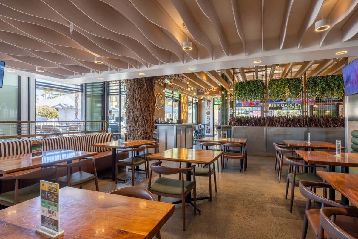 The indoor dining room with booth and table seating under the sculpted ceiling